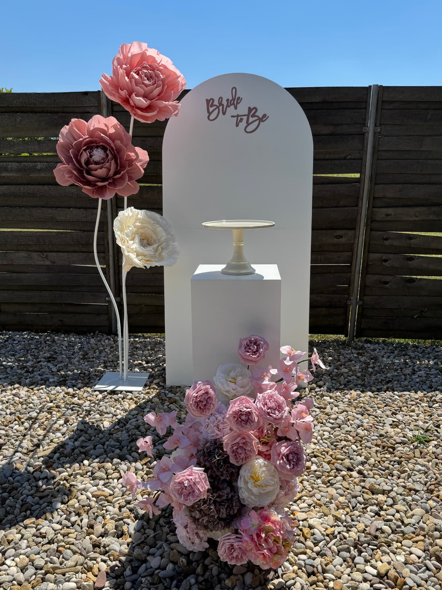 Bride to Be postava s bijelim lukom, postamentom i roza cvjetnom kompozicijom