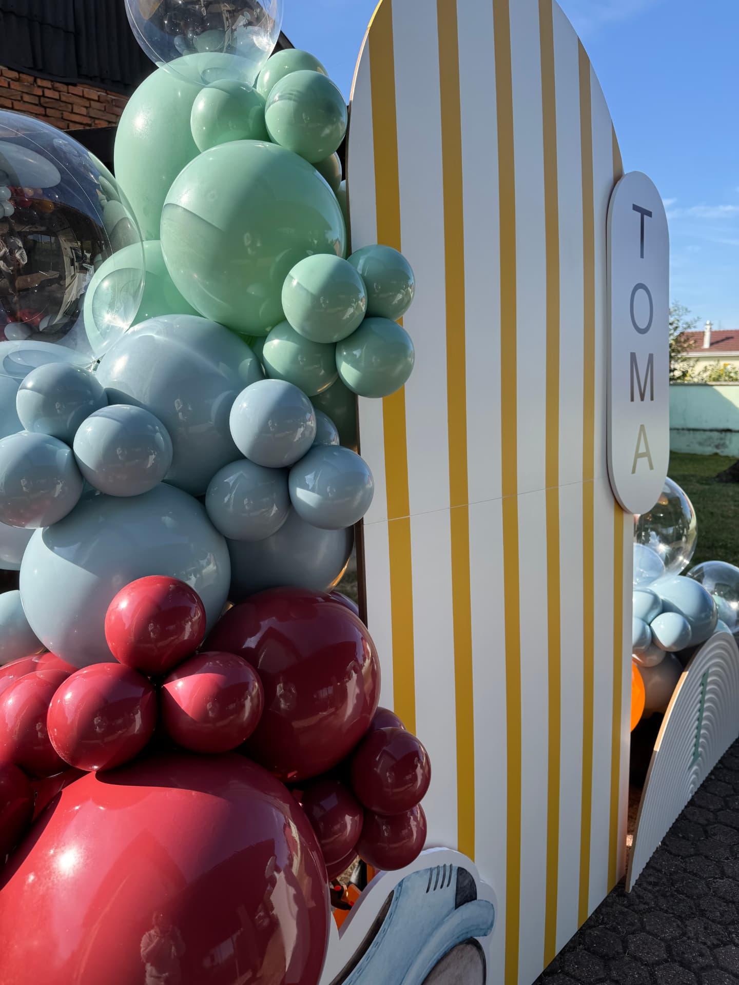 Šarena balonska instalacija uz prugasti luk s imenom